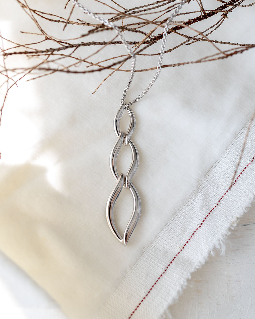 Entwine Twine Link Trio Necklace on a styled background