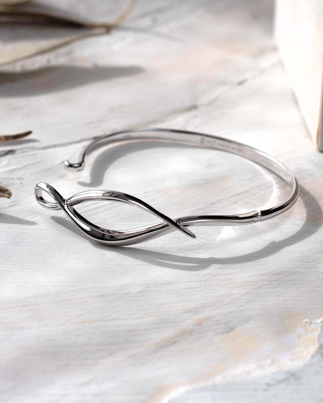 Entwine Twine Twist Hinged Bangle on a styled background