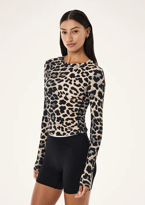 Woman wearing a leopard print long-sleeve top and black shorts on a white background