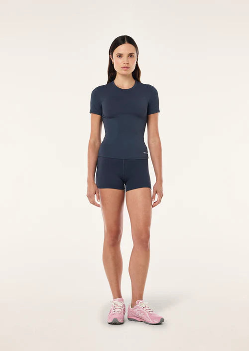 Woman wearing a navy athletic outfit on a white background