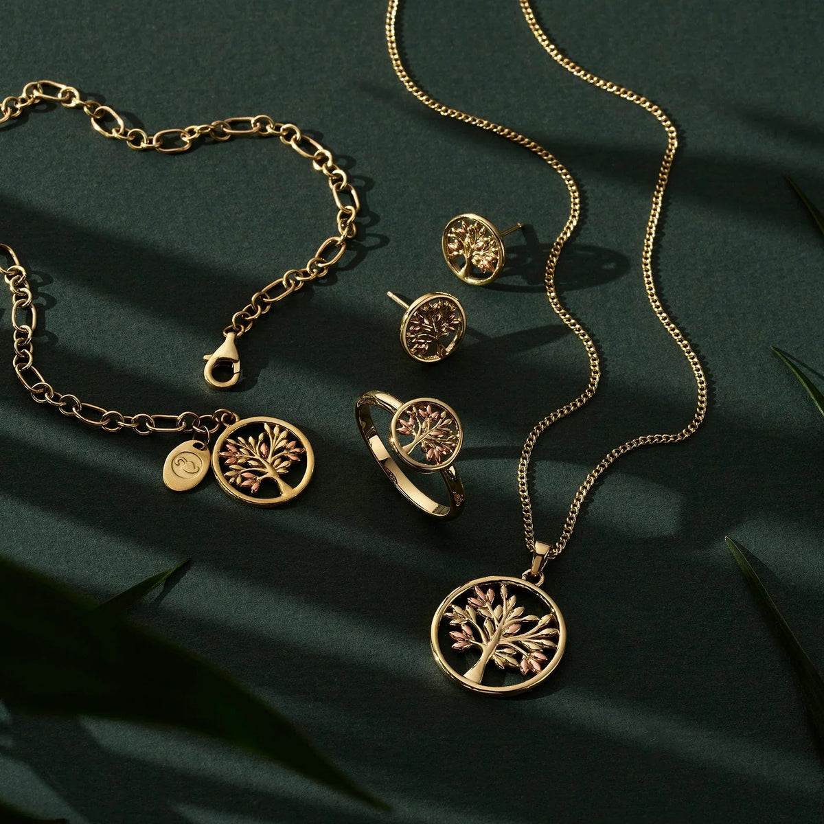 Gold jewelry set on a dark green surface.
