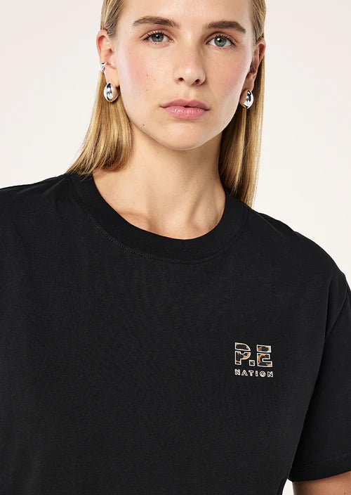 Person wearing a black t-shirt with a logo on a plain background