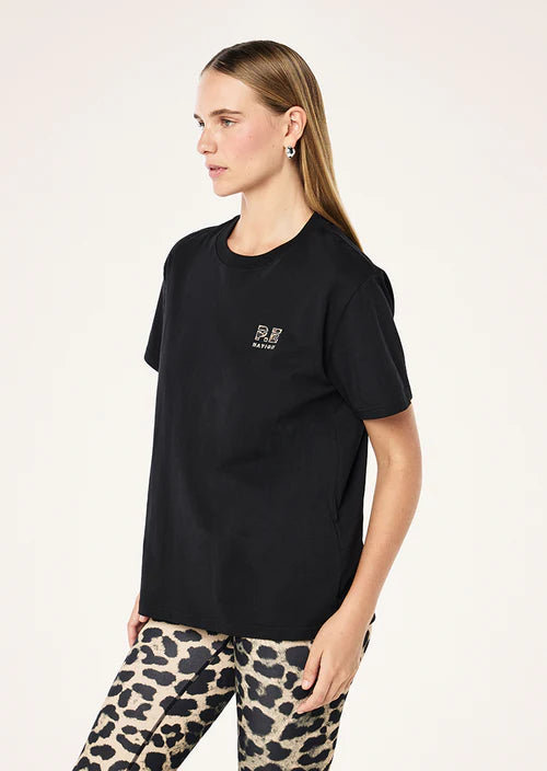 Woman wearing a black t-shirt with a logo and leopard print pants on a white background