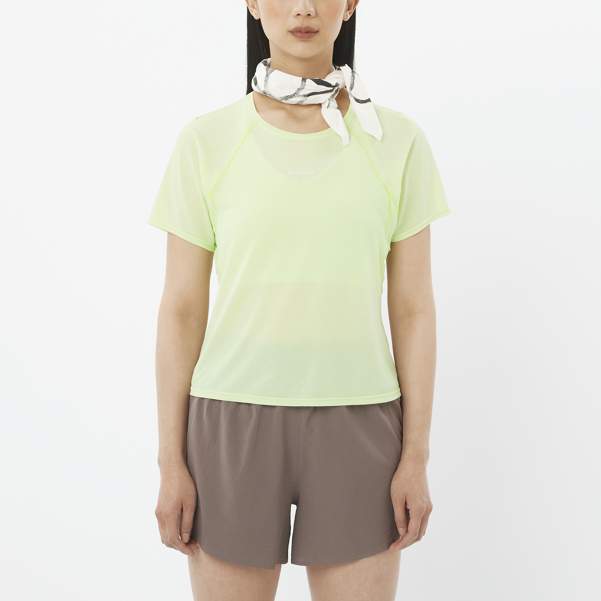 Person wearing a light green shirt and brown shorts on a white background