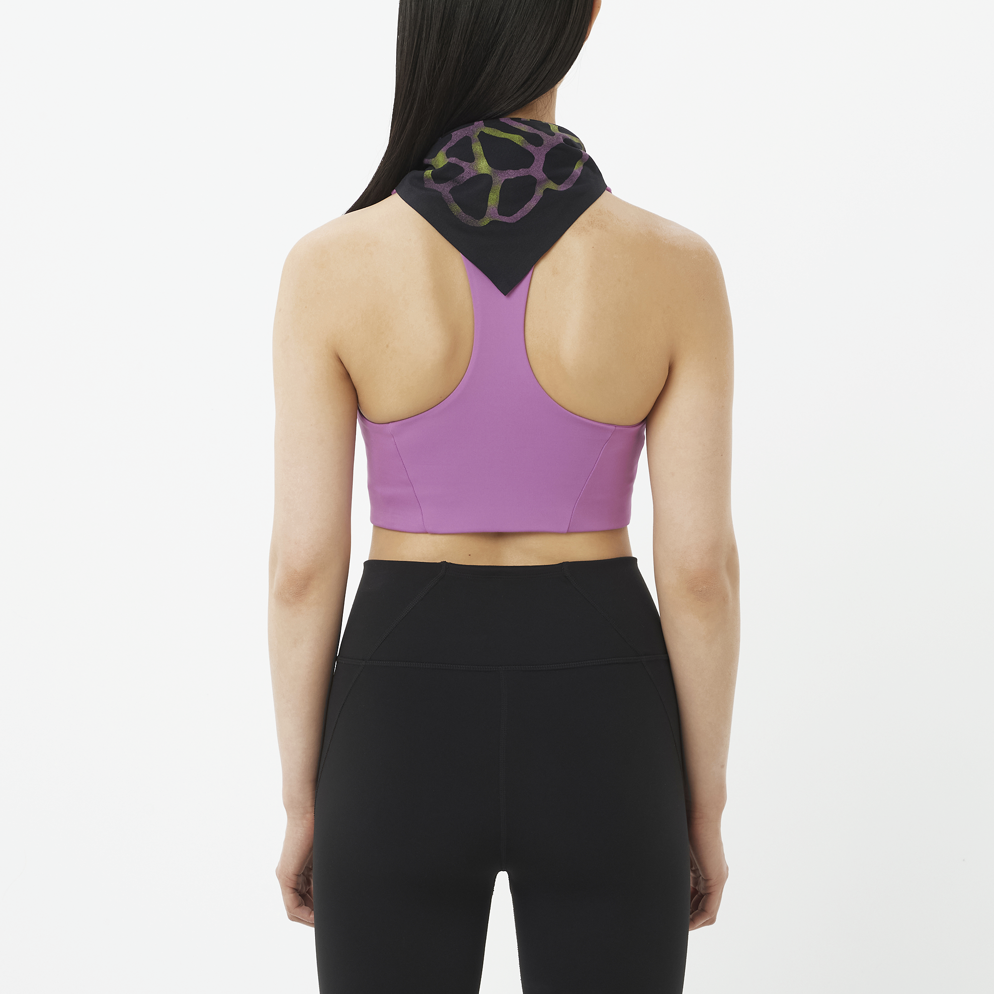Person wearing a purple sports bra and black leggings on a white background