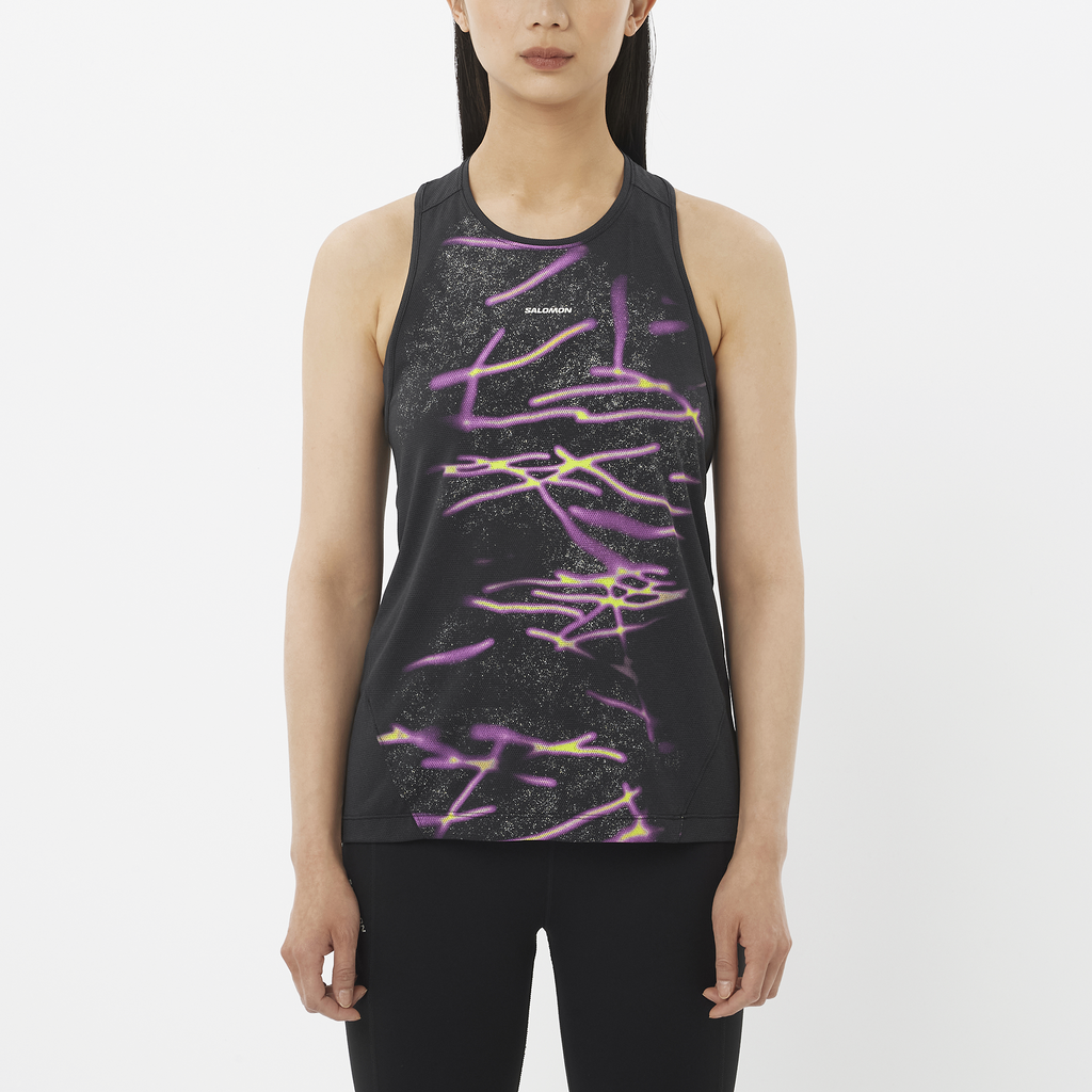 Woman wearing a black sleeveless top with colorful abstract design on a white background