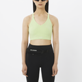 Woman wearing a light green sports bra and black leggings with a Salomon waist bag on a white background