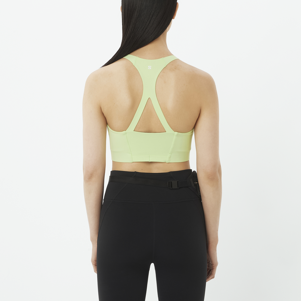 Person wearing a light green sports bra and black leggings on a white background