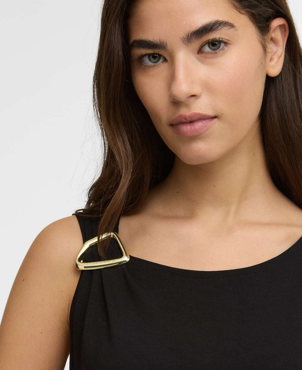 Woman wearing a black top with a gold buckle detail on a white background