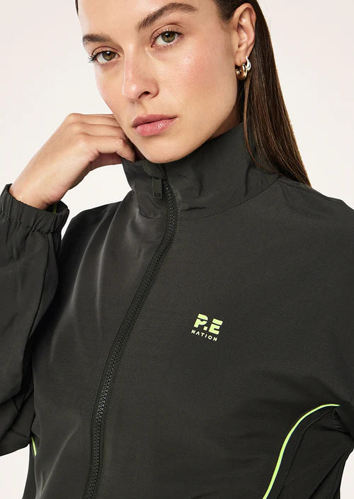 Woman wearing a grey  jacket with a logo on a light pink background