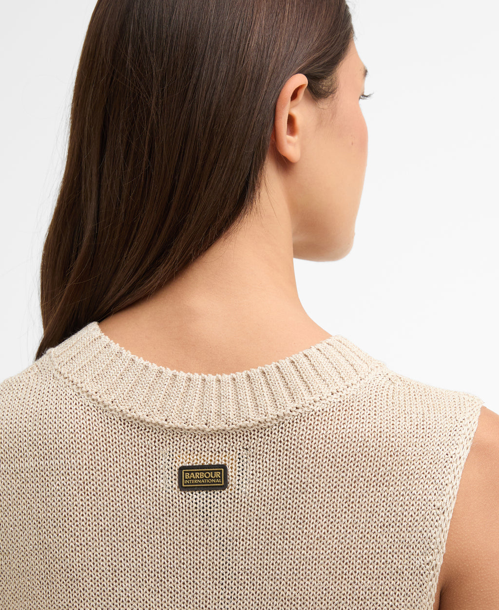 Beige sleeveless sweater with a brand label on a plain background