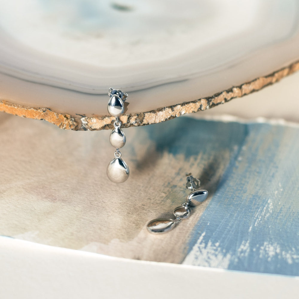 Silver earrings with three raindrop-shaped pendants.