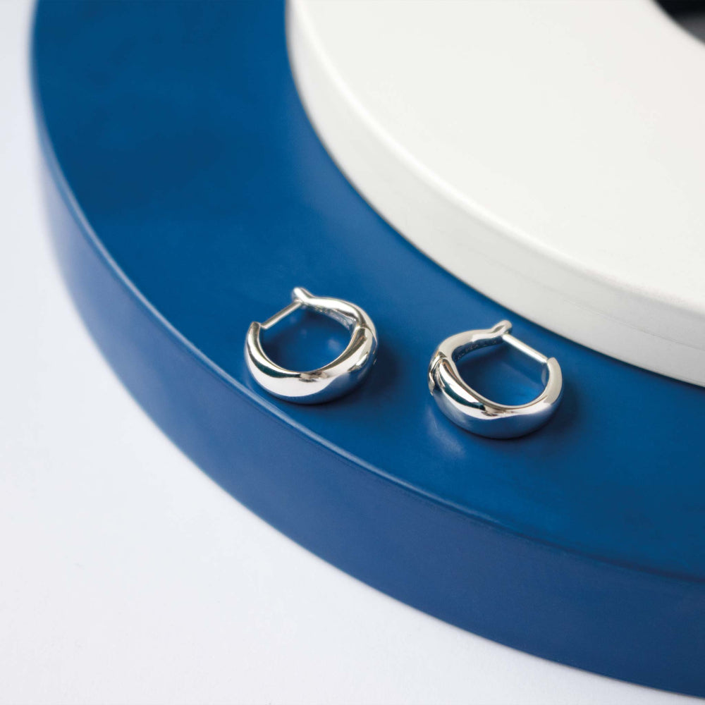 The Kit Heath Bevel Cirque hinged huggie hoops, a silver metal pair from Kit Heath, available at OD’s Jewellers in St Helens