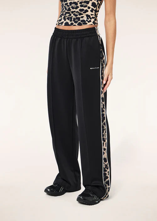 Person wearing black track pants with a leopard print side stripe on a white background