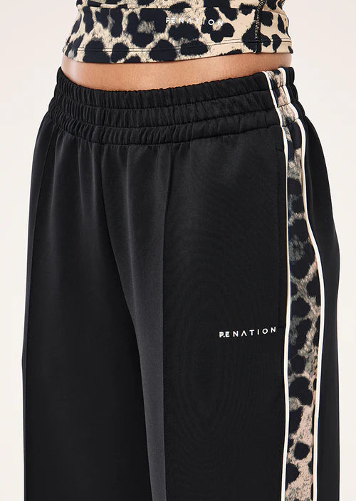Black track pants with leopard print side strip and cropped top on a white background