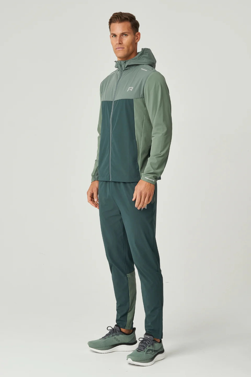 Man wearing a green tracksuit with a hood  with reprimo logo on chest on a white background
