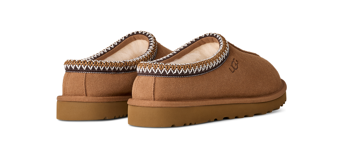 Pair of brown slippers with decorative trim on a white background