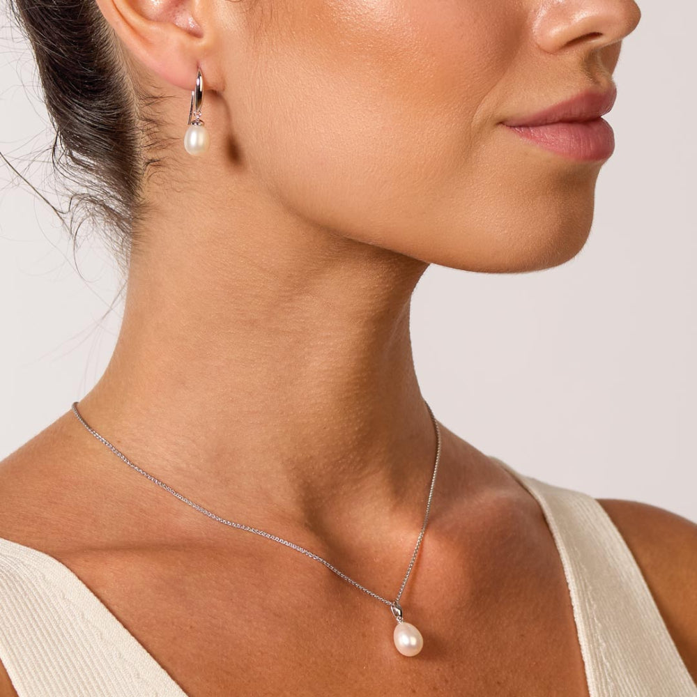 Woman with pearl jewelry set consisting of earrings and necklace. 
