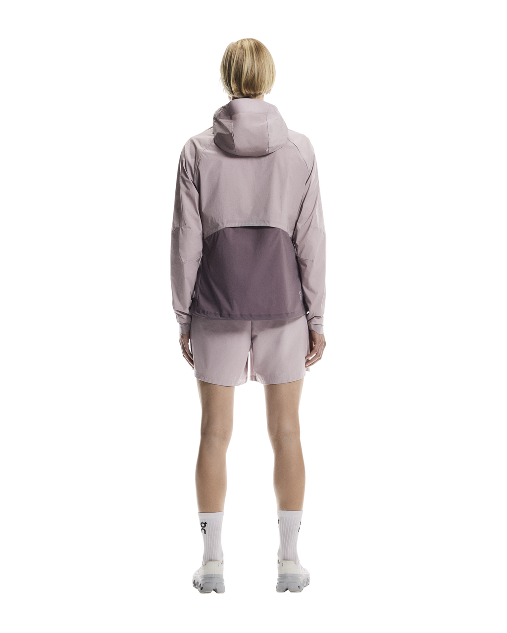 Person wearing a light gray jacket with a color block design on a white background