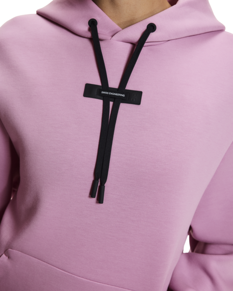 Close-up of a pink hoodie with black drawstrings and a brand logo.