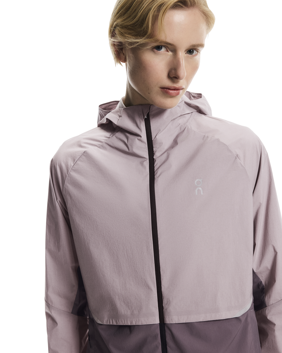 Person wearing a light purple jacket with a brand logo on a white background
