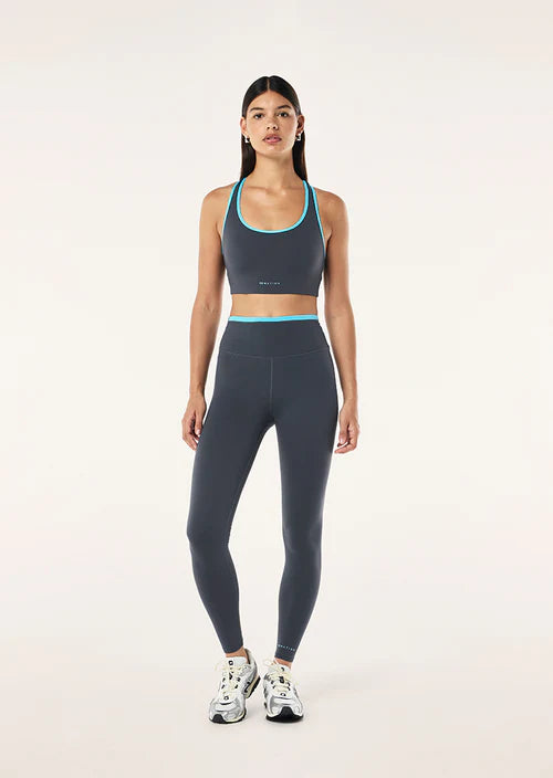 Woman wearing a gray sports bra and leggings set on a white background