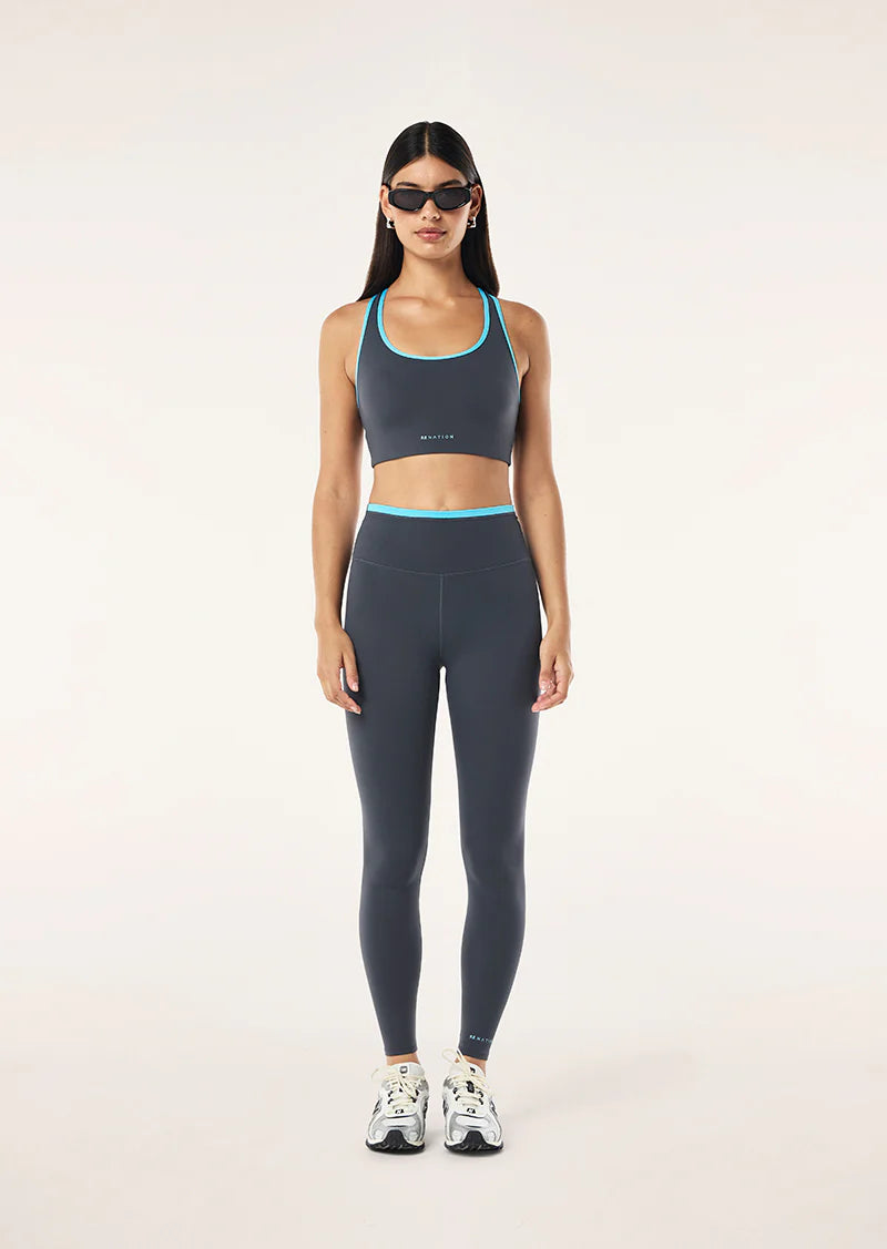 Woman wearing a gray sports bra and leggings set on a white background