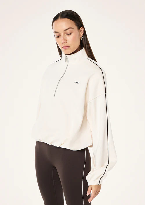 Woman wearing a white athletic jacket with black accents on a white background