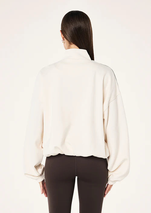 Woman wearing a white athletic jacket with black accents on a white background.