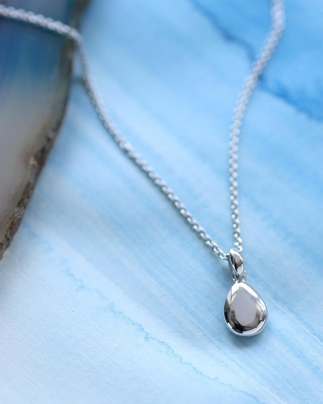 Pebbles Droplet Necklace on a styled background