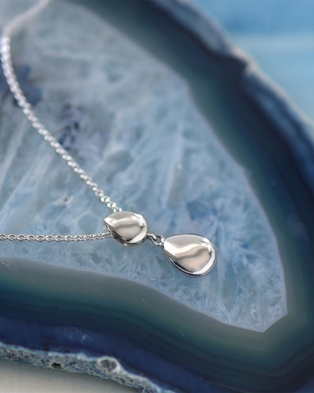 Pebbles Twin Droplet Necklace on a styled background