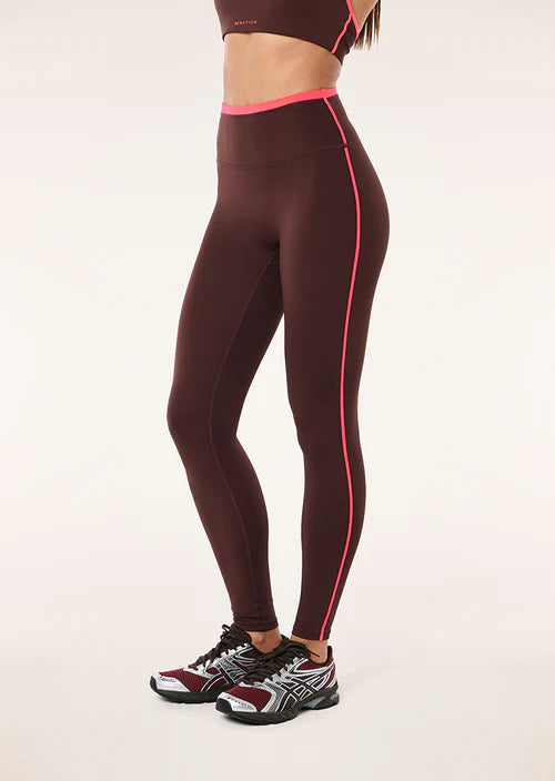Brown leggings with pink accents worn by a person on a white background