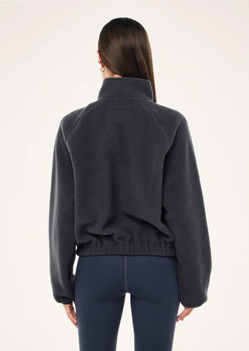 Person wearing a dark blue sweater and dark blue pants on a white background