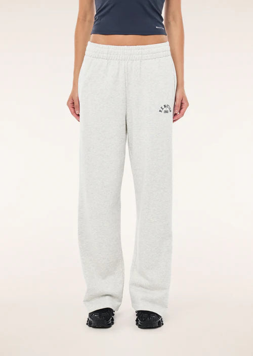 Person wearing white sweatpants with a logo on a plain background