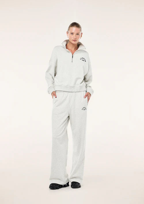 Person wearing a light gray tracksuit with a brand logo on a white background