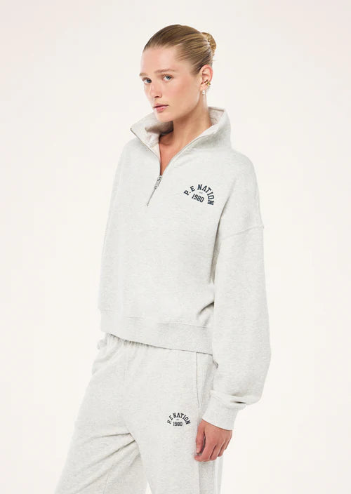 Person wearing a light gray hoodie with branding on a white background