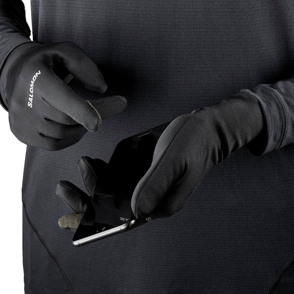 Person wearing Salomon gloves using a phone with a black background