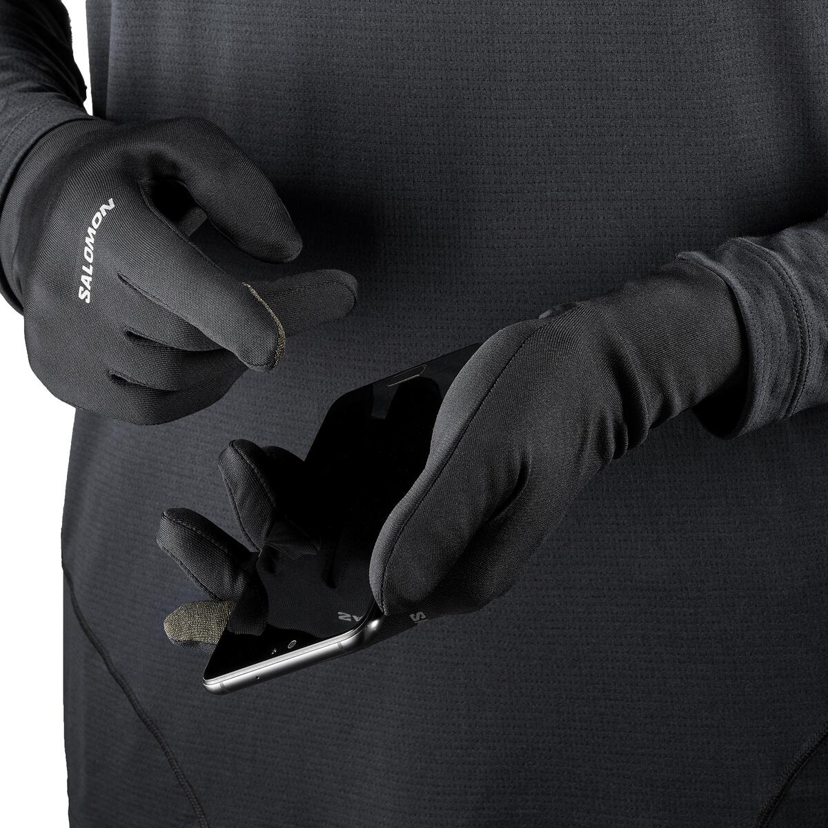Person wearing Salomon gloves using a phone with a black background