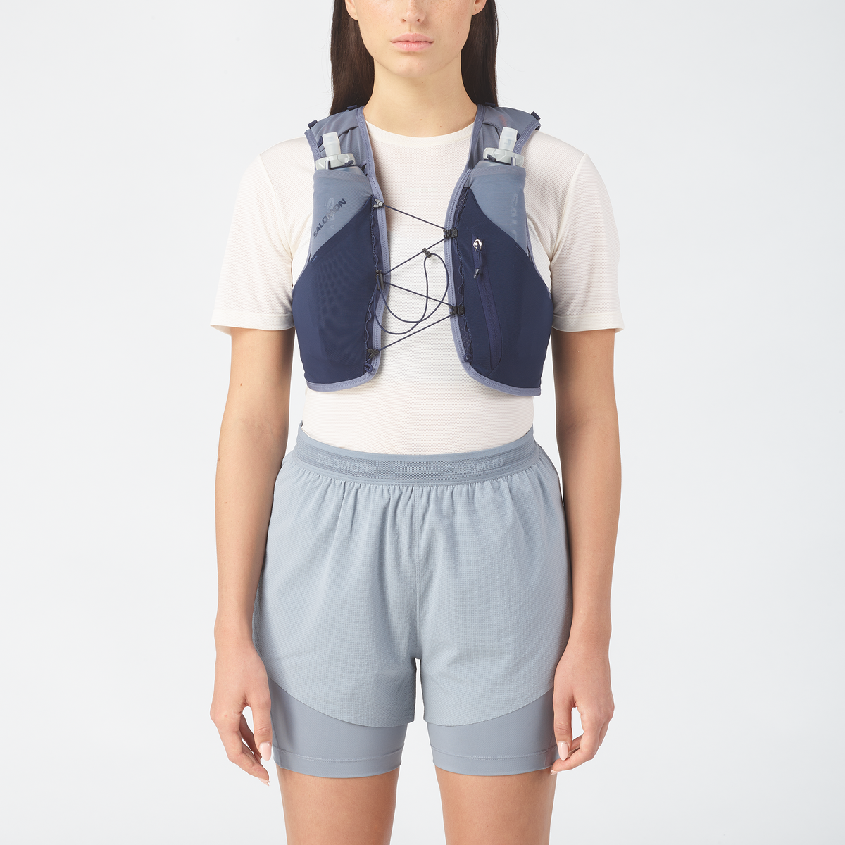Person wearing a blue hydration  vest and shorts on a white background
