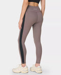 Person wearing brown leggings with black side stripe on a white background