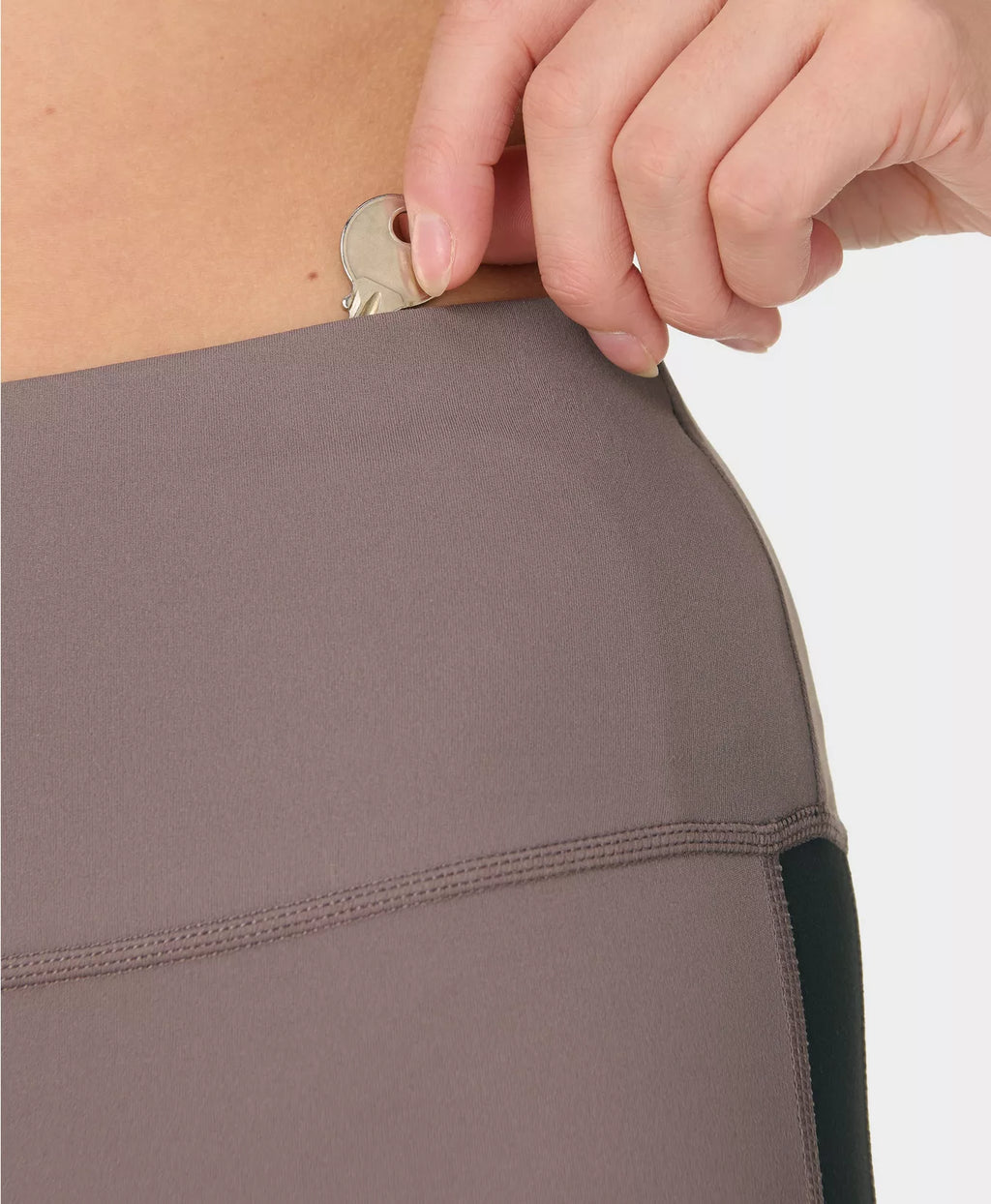 Close-up of a person adjusting a button on a gray garment against a white background
