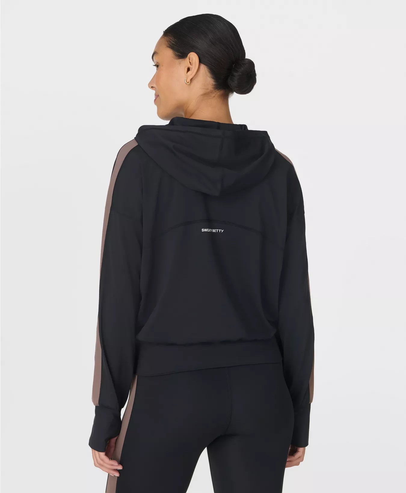 Person wearing a black hoodie with a visible brand logo on a white background