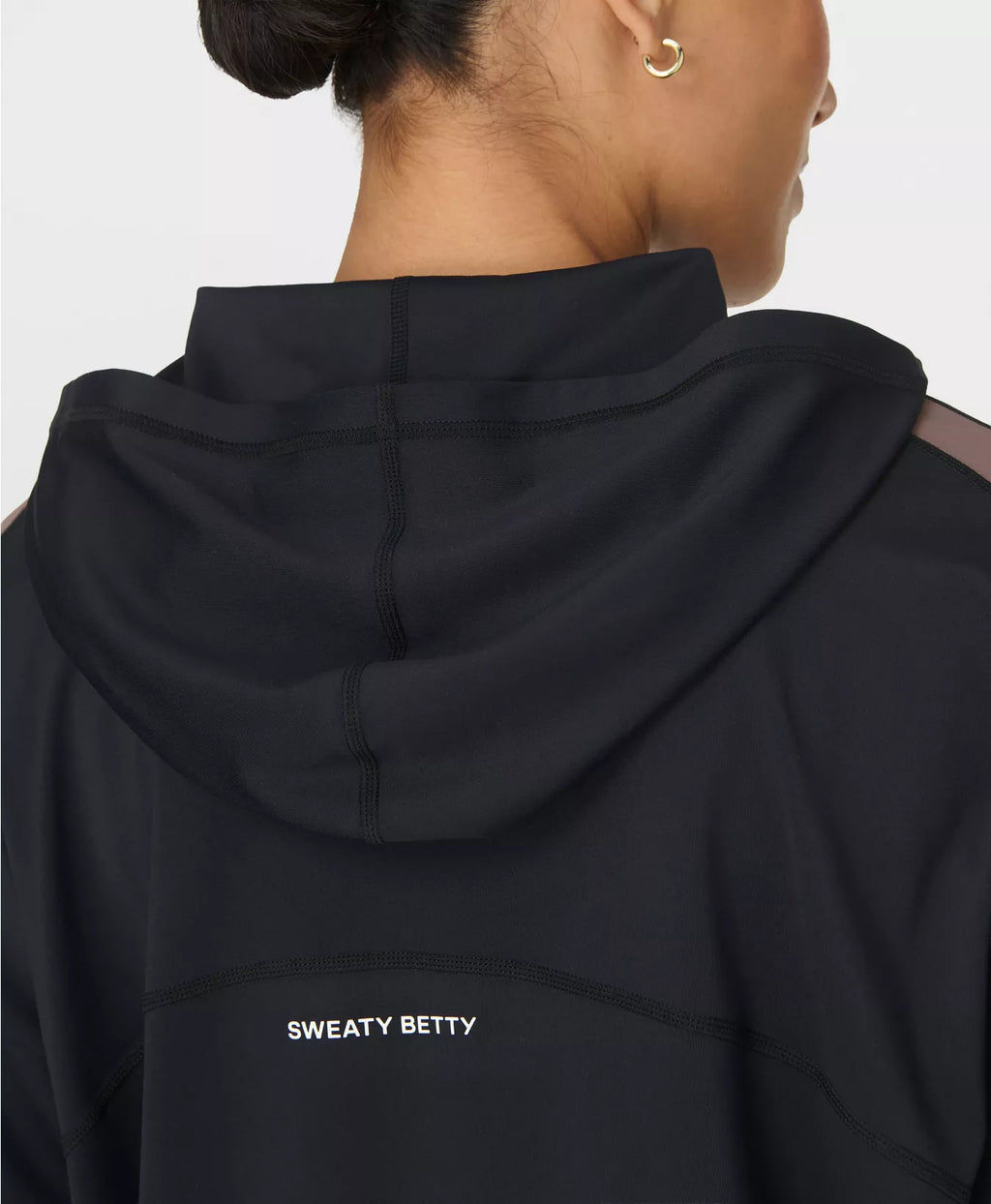 Black hoodie with 'Sweaty Betty' branding on the back, worn by a person.