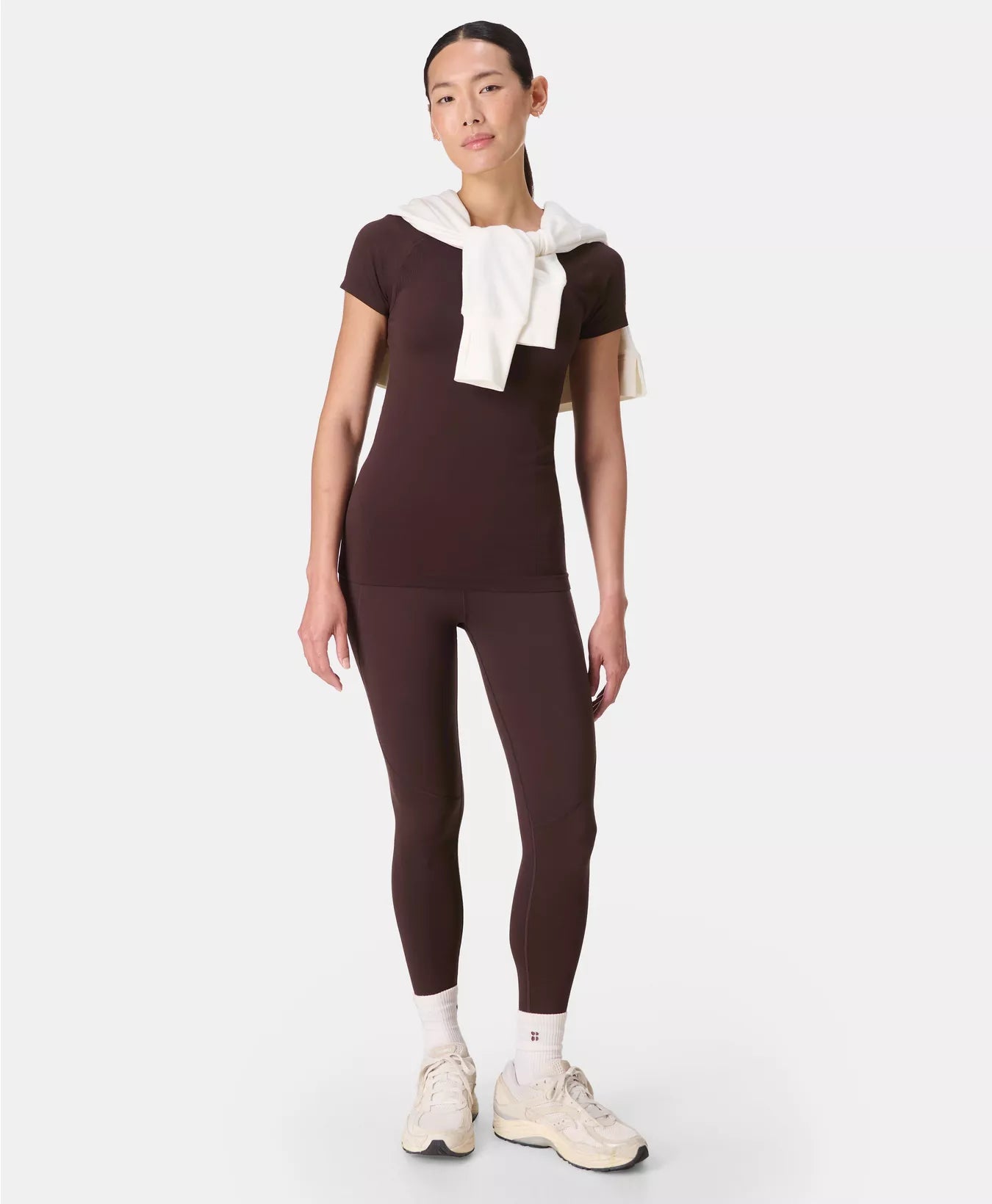 Person wearing a brown outfit with a white towel on a white background