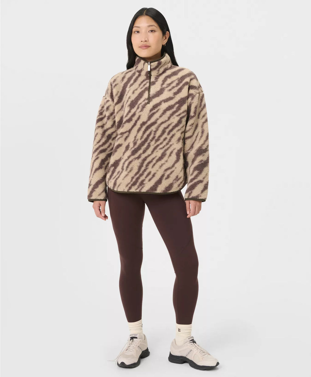 Person wearing a zebra print fleece jacket and dark leggings on a white background
