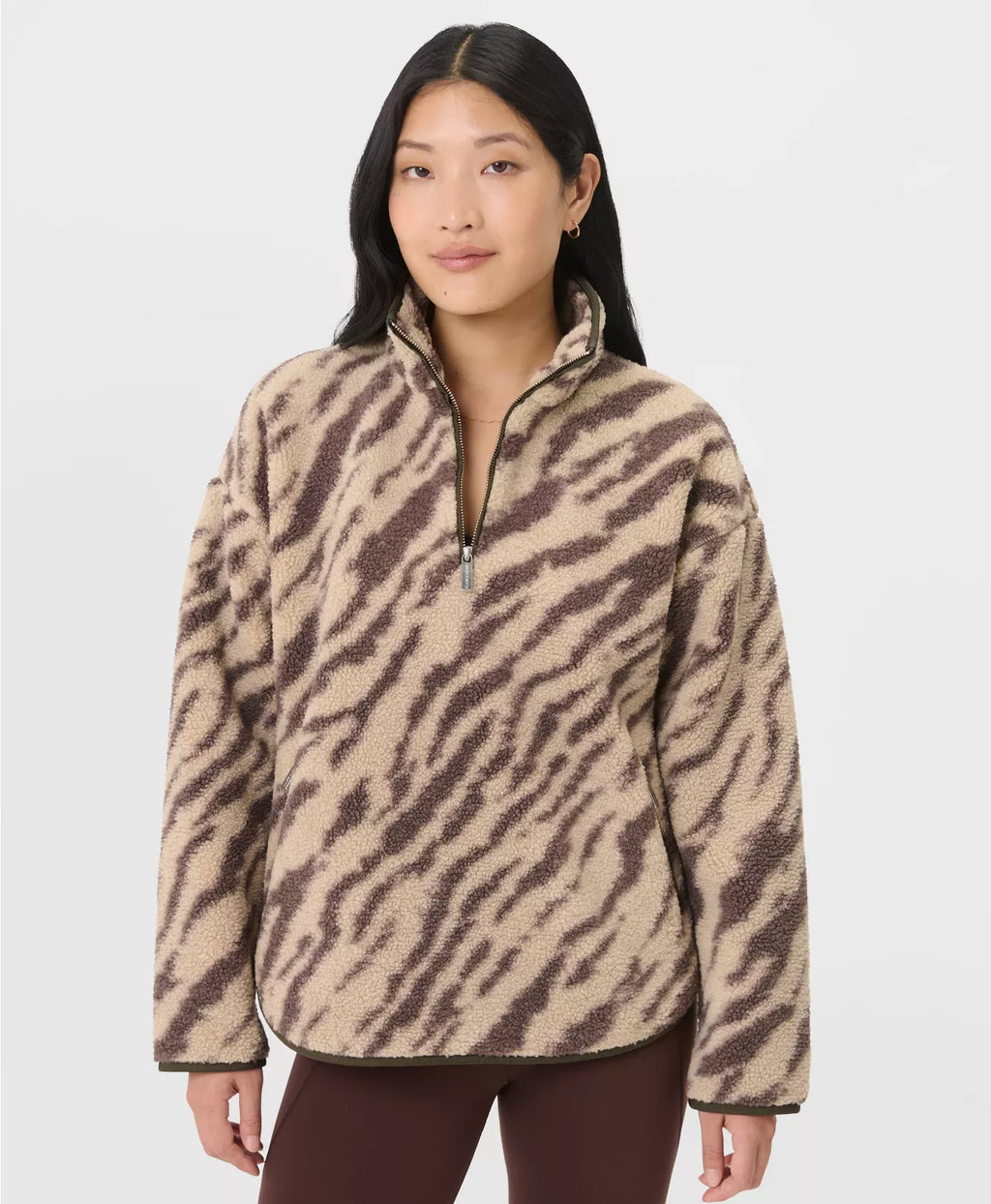 Woman wearing a beige and brown zebra print pullover on a white background