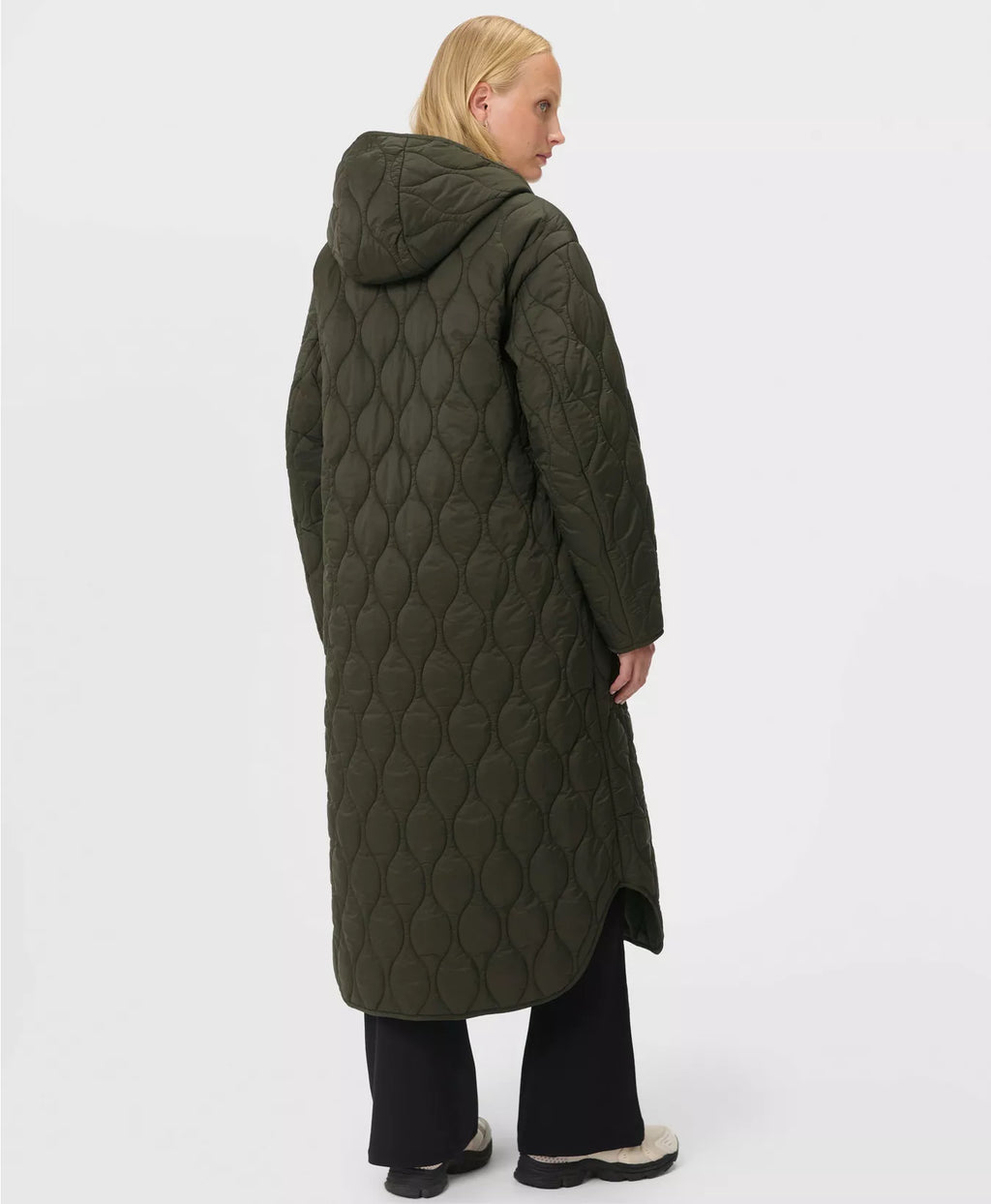 Person wearing a long quilted green coat on a white background