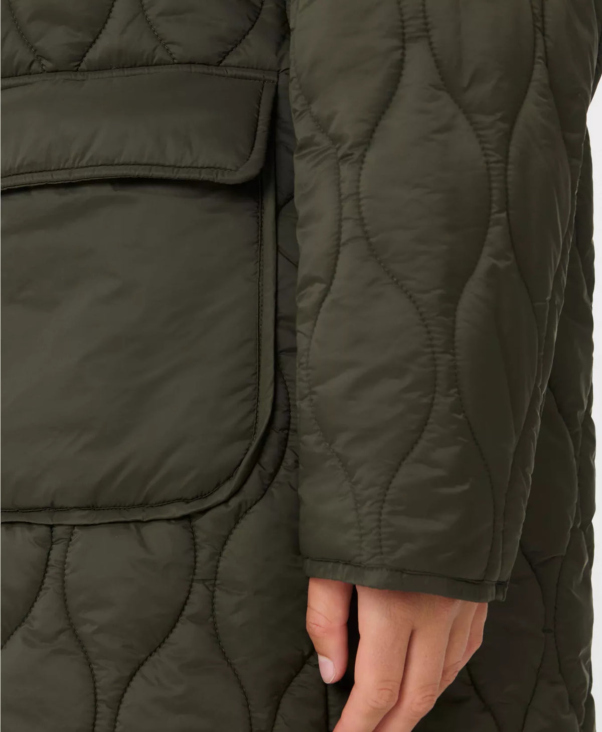 Close-up of a person wearing a quilted green jacket with a hand visible.