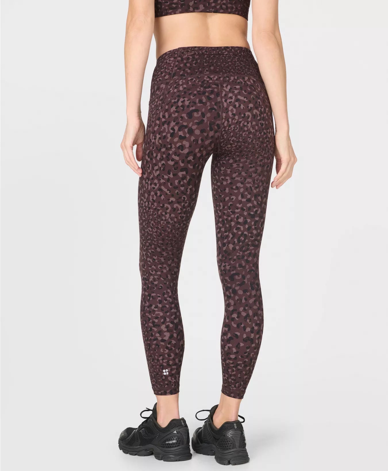 Person wearing maroon leopard print leggings on a white background