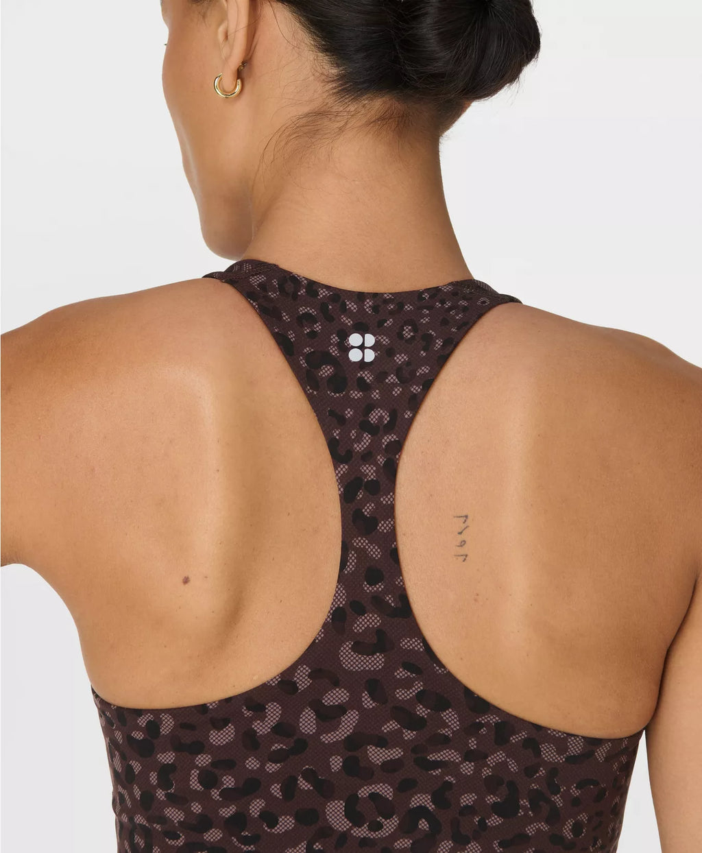 Person wearing a dark patterned sports bra on a light background
